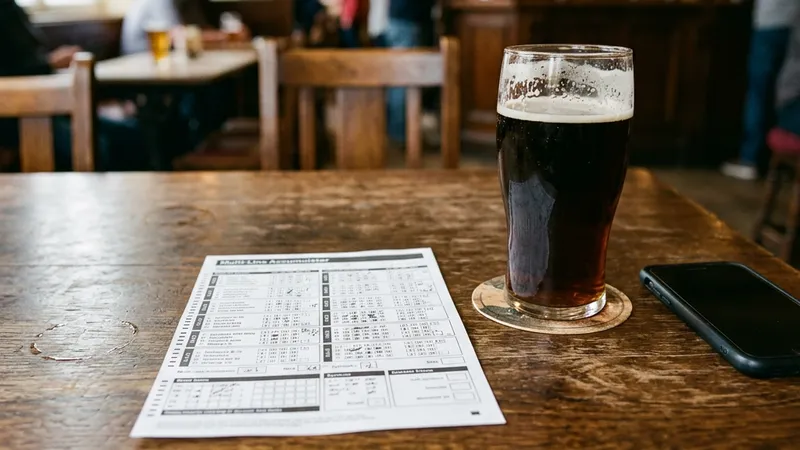 A betting slip showing a multi-leg accumulator beside a phone and a pint on a pub table